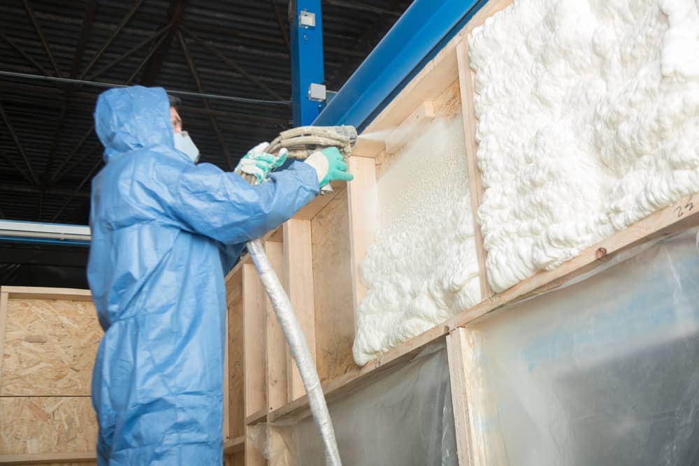 A worker insulating the walls of an industrial building