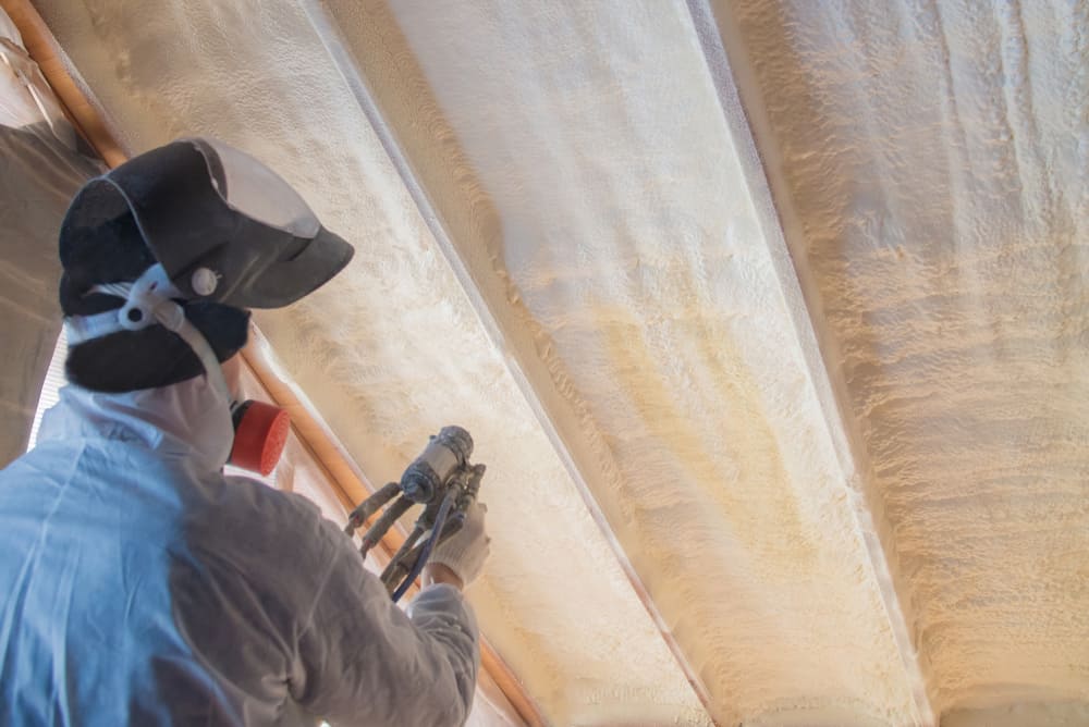 A person spraying insulation in an industrial building